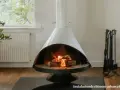 Chimenea moderna con fuego encendido, rodeada de elementos decorativos y un juego de herramientas. Un ejemplo de estufas seguras para tu hogar.
