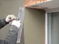 Lavori di intonacatura attorno alle finestre, con un cappotto che protegge le spallette. Si nota lo spessore dello strato di intonaco.