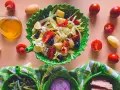 Un'insalata di patate napoletana colorata con pomodorini, olive e lattuga, servita in una ciotola a forma di foglia.