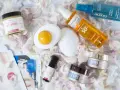 Kosmetyki do pielęgnacji: kremy, serum, mgiełka do ciała, olejek ochronny i peeling ryżowy. Całość ułożona na płatkach kwiatów, tworząc wiosenny, roc.