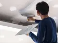 Un trabajador aplica masilla al techo, resolviendo la duda de si que se pinta primero el techo o las paredes.