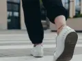Kobieta w białych sneakersach idzie po pasach, licząc ile kroków dziennie.