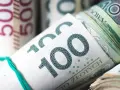 Zwijane banknoty 100 zł i 50 zł związane gumką.