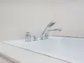 Elegancka bateria wannowa jednootworowa z chromowanymi elementami i słuchawką prysznicową, idealna do nowoczesnej łazienki.