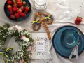 En midsommardukning med jordgubbar, blomsterkrans, en pretzel med svenska flaggor och en "Skål!"-bok. Ett personligt ljus för firandet.