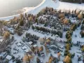 Wintercamping im Erzgebirge: Wohnmobile und Wohnwagen stehen im Schnee auf einem Campingplatz am See, umgeben von verschneiten Bäumen.