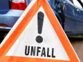 Warnschild "Unfall" vor beschädigtem Auto. Nach einem Verkehrsunfall kann eine Vorstandsbeschwerde bei der Versicherung nötig sein.