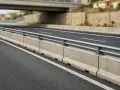 Barriera spartitraffico in cemento, conforme all'art. 175 CDS, con guardrail metallico su strada asfaltata.