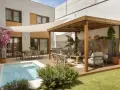 Modernos patios con piscina, zona de estar bajo pérgola de madera y comedor exterior.