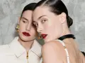 Due modelle con labbra audaci e un intenso colore rossetto, con capelli tirati indietro e orecchini dorati.