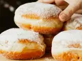 Stos puszystych pączków oprószonych cukrem pudrem. Idealne na tłusty czwartek, te fit pączki kuszą apetycznym wyglądem.