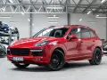 Czerwony Porsche Cayenne GTS lśni w salonie, gotowy na podbój dróg.