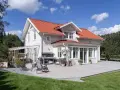 Vitt hus med rött tak och stor altan. Perfekt för att behandla altan och njuta av sommaren.