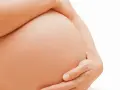 Dłoń obejmuje ciążowy brzuch. Zaparcia w ciąży to częsty problem, ale można sobie z nimi radzić.