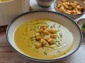 Un cremoso puré de verduras, adornado con picatostes crujientes y un chorrito de aceite de oliva.