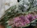 Zbliżenie na kwarc arbuzowy, ukazujące jego zielono-różowe pasma i krystaliczną strukturę. Kwarc arbuzowy właściwości: piękno natury.