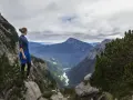 Donna in cima a una montagna, contemplando un vasto paesaggio alpino. Il vero hiking significato è nella libertà e nella vista mozzafiato.