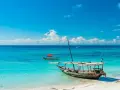 Piękna plaża na Zanzibarze, turkusowa woda, łodzie i marzenia o wakacjach. Może nawet o zarobieniu tam zanzibar dolary.