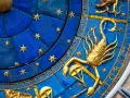 Złoty skorpion, symbol zodiaku, na niebieskiej tarczy z gwiazdami i cyframi.