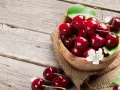 Schale mit Kirschen auf Holztisch. Kirschen sind oft histaminreich, aber diese sehen köstlich aus.