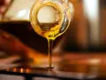 Olio d'oliva dorato cola da una bottiglia. Scopri come conservare l'olio di oliva per mantenerne intatto il sapore.