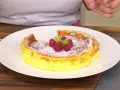 Tarta de queso Arguiñano recién horneada, espolvoreada con azúcar glas y decorada con frambuesas y menta.
