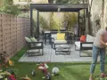 Donna annaffia fiori in un giardino con mobili moderni e un triciclo, un esempio di giardino idee originali.