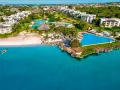 Widok z samolotu na tropikalny kurort na Zanzibarze z białymi budynkami, basenami i plażą nad turkusowym oceanem.