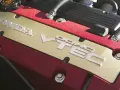 Złota pokrywa silnika Honda z napisem VTEC, otoczona czerwonym, błyszczącym wykończeniem.