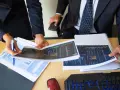 Dos personas analizan gráficos financieros, discutiendo los diferentes tipos de auditorías y sus implicaciones para el negocio.