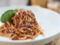 Pyszne spaghetti bolognese, bogate w mięso i sos pomidorowy, posypane parmezanem i udekorowane listkiem bazylii. Idealny przepis na obiad.