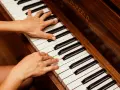 Dłonie grające na pianinie, tworząc muzyczną progresję.