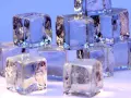 Eiswürfel stapeln sich, glitzernd und durchscheinend. Sie zeigen, wie kalt Eis werden kann, mit gefrorenen Einschlüssen und scharfen Kanten.