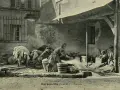 Des femmes s'affairent à laver le linge autrefois, dans une cour. Des enfants observent ce travail pénible.