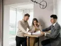 Para, która ogląda dokumenty z agentem nieruchomości, zastanawia się, ile zarabia agent nieruchomości.