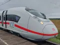 Nowoczesny, biały pociąg ICE 3neo z czerwonym pasem, stojący na peronie.