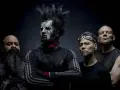 Quatre hommes, dont un avec un maquillage facial blanc et une crête, posent pour une photo. Le groupe Static X semble prêt à monter sur scène.