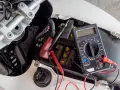 Multimetro collegato alla batteria di uno scooter per verificarne lo stato, un passo fondamentale per capire come caricare batteria scooter.