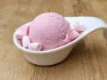 Eine Kugel rosa Bubble Gum Eiscreme mit Marshmallows in einer weißen Schale auf Holzhintergrund.