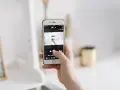 Dłoń trzyma smartfon, na ekranie którego widać aplikację do robienia zdjęć. To jakby snapbridge po polsku, ułatwiający dzielenie się wspomnieniami.