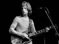 Pete Ham, mit gestreiftem Shirt und Gitarre, blickt konzentriert auf die Bühne.