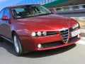 Czerwone Alfa Romeo 159 na drodze. Kierowca w białej koszulce, pozytywne opinie o tym modelu potwierdzają jego sportowy charakter.
