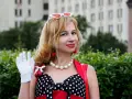 Una mujer con guantes blancos saluda, luciendo un vestido de lunares y cerezas. ¡Buenos días, señorita en francés!