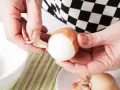 Dłonie obierają jajka na twardo. Skorupka łatwo odchodzi, odsłaniając białe wnętrze.