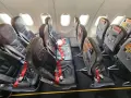 Puste fotele w samolocie, czerwone pasy bezpieczeństwa. Czy warto lecieć Pegasus Airlines? Opinie pasażerów są różne.