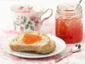 Fetta di pane con marmellata di anguria, tazza da tè fiorita e barattolo di marmellata.