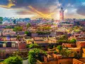 Marrakesz w styczniu: słoneczna pogoda nad miastem z minaretem Koutoubia w tle. Dachy pełne zieleni i anten satelitarnych.