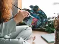 Une artiste aux cheveux roux mélange des couleurs vives sur sa palette, prête à peindre. Apprenez comment utiliser la peinture acrylique pour créer de telles œuvres.