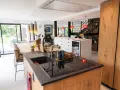 Îlot de cuisine moderne avec plan de travail en granit, évier noir et plaque à induction. La **rénovation cuisine bois massif** se révèle dans les placards et l'îlot central.