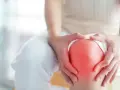 Hände umfassen ein schmerzendes Knie, das rot aufleuchtet, ein Zeichen für Arthrose im Knie.